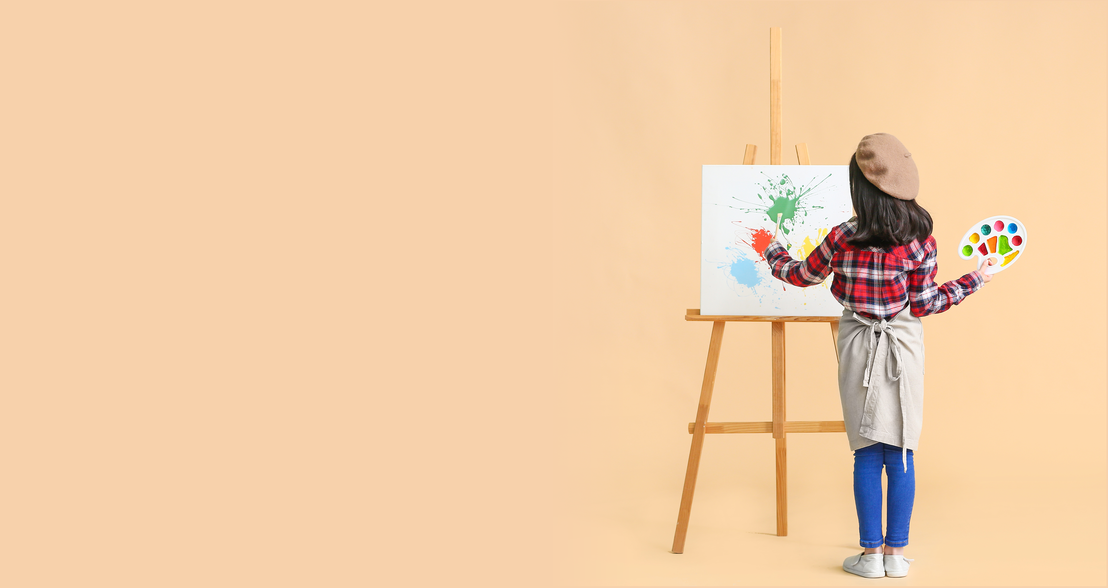 Girl standing in front of an easel with a painting on a beige background