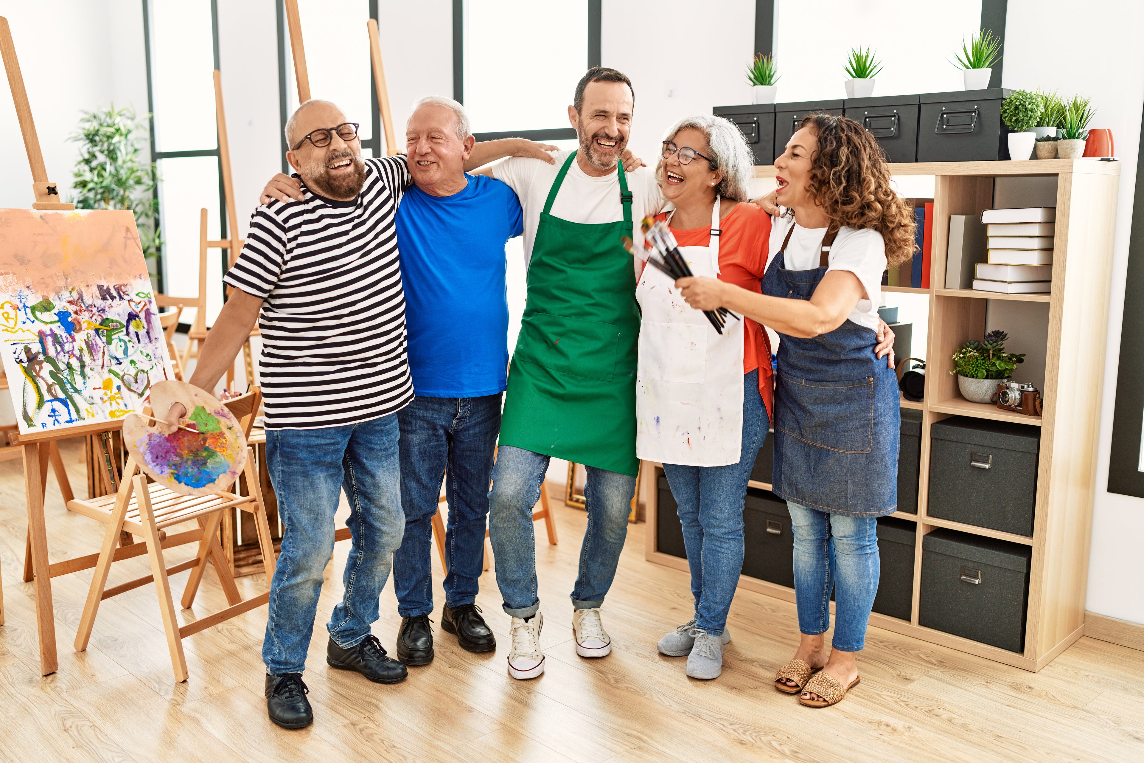 Group of artists hugging and laughing in a art studio.