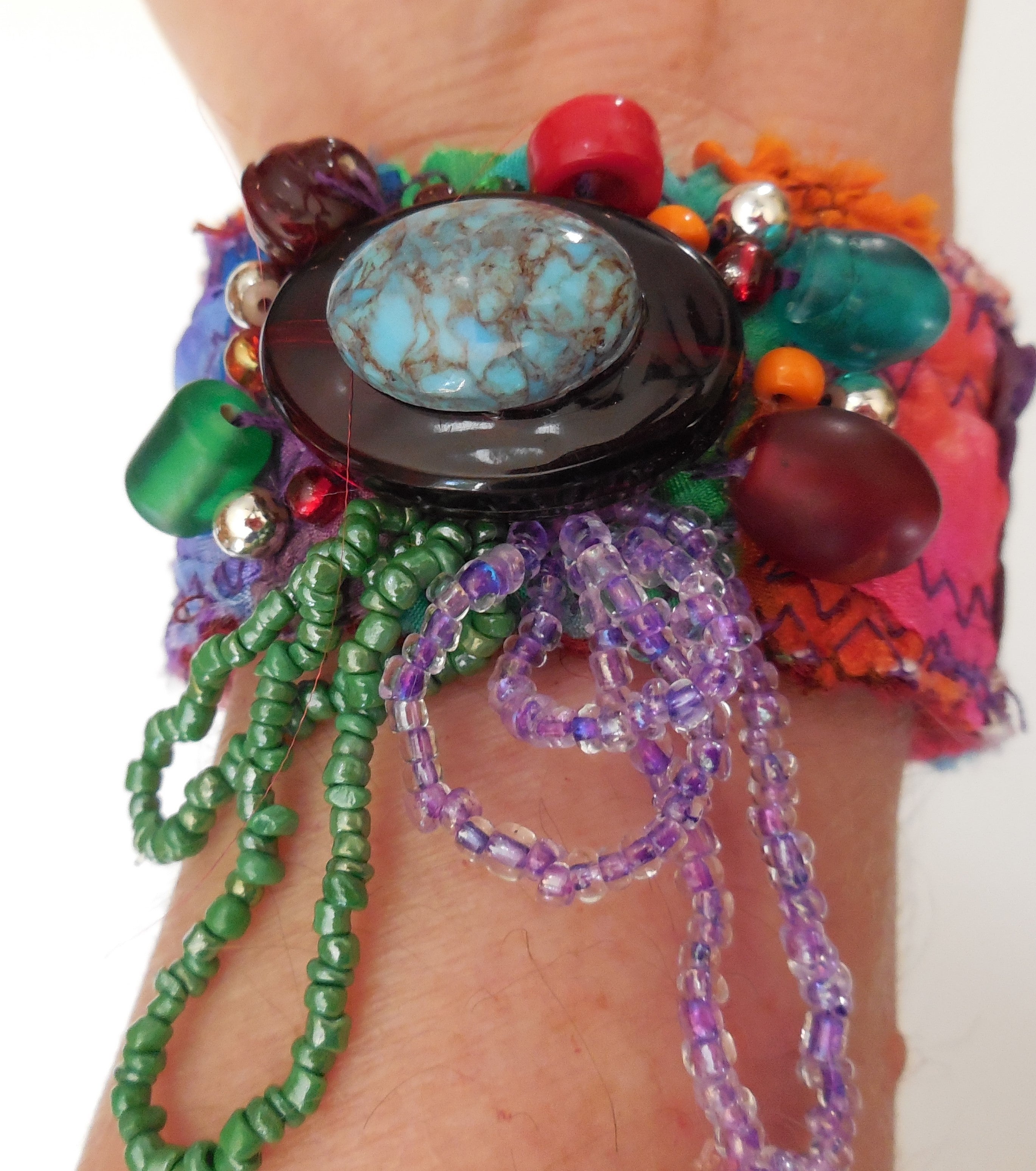 Colorful beaded bracelet with a large turquoise stone on a wrist against a white background