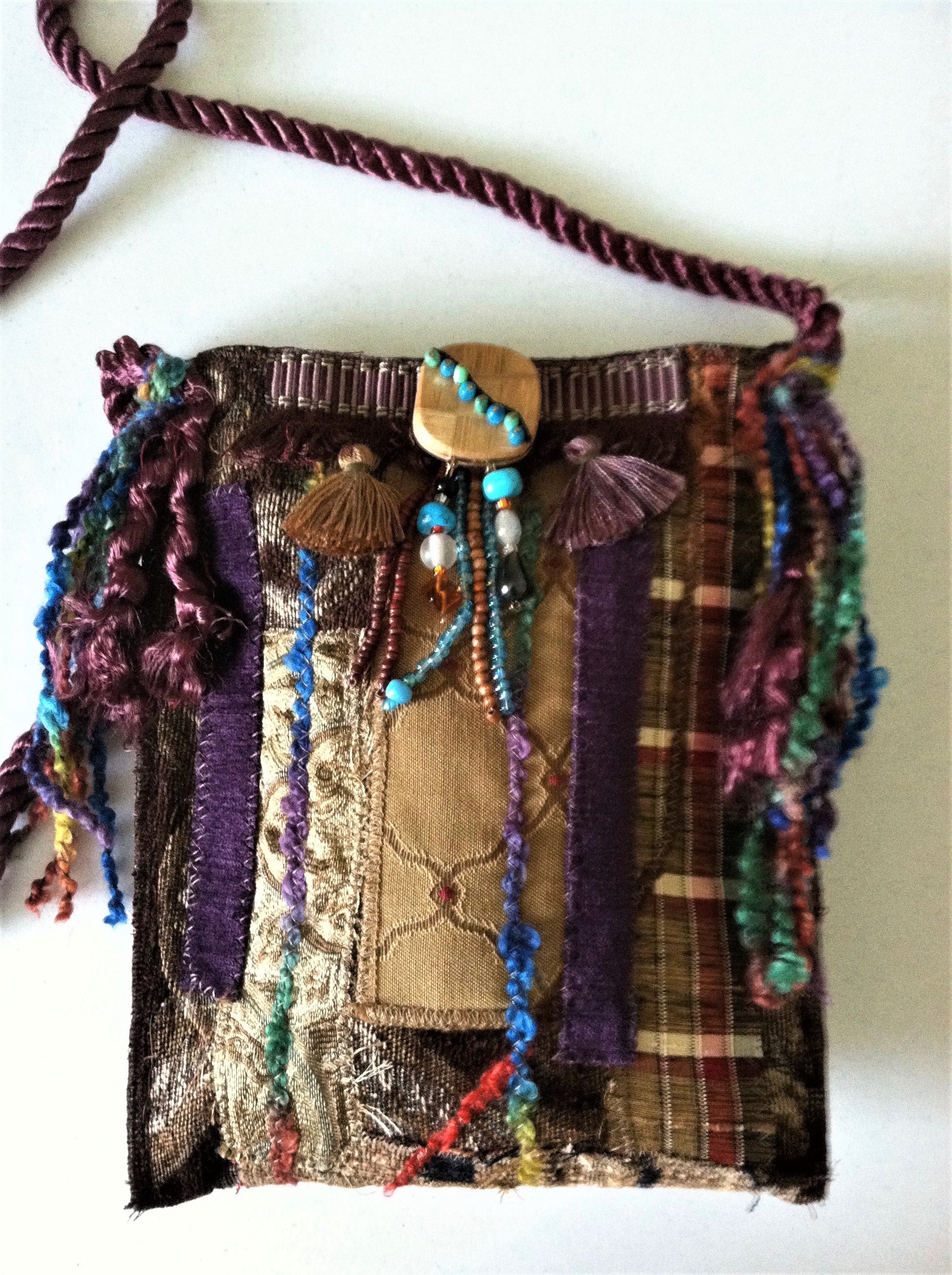 Textile art  handbag with colorful threads and beads on a white background