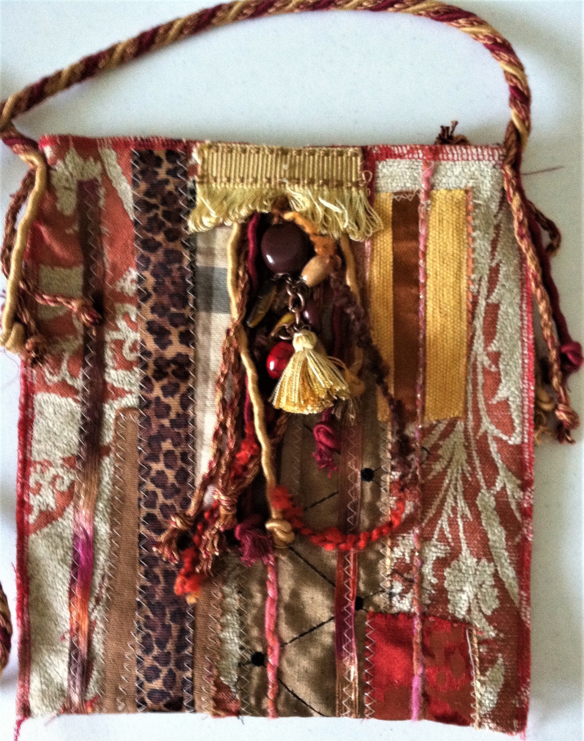 Decorative handbag with fabric, ribbons, and beads on a white background