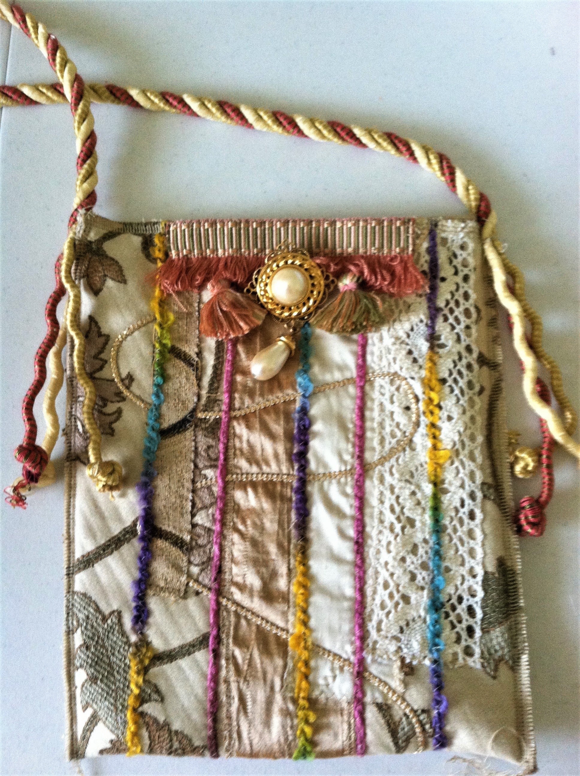 Decorative handbag with embroidered patterns, tassels, and beads on a white background